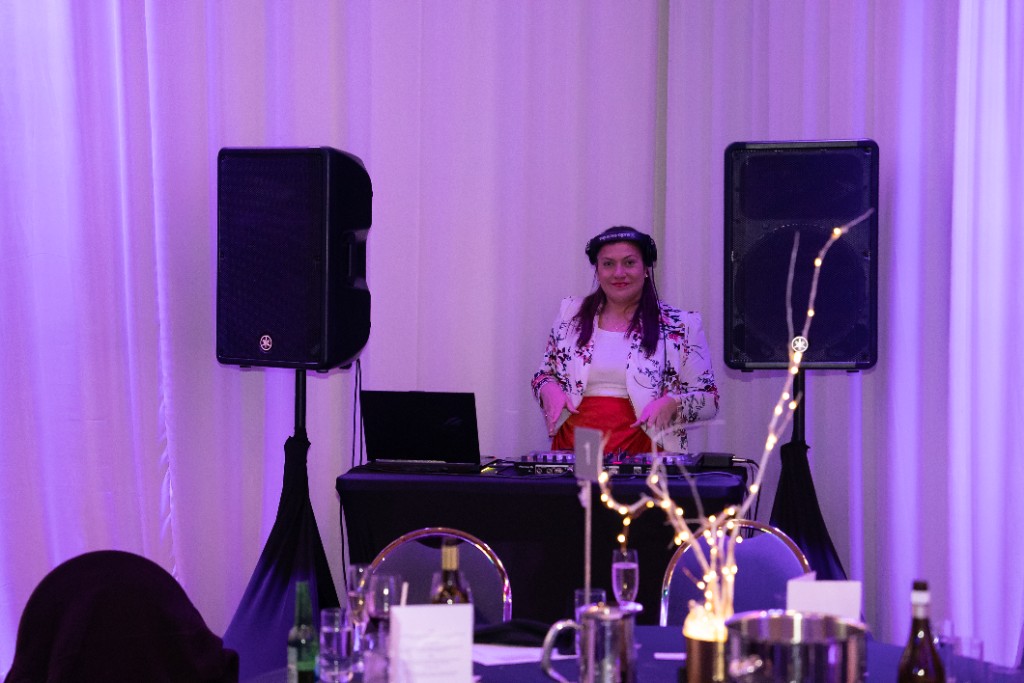 Corporate event DJ setup with professional speakers and ambient uplighting