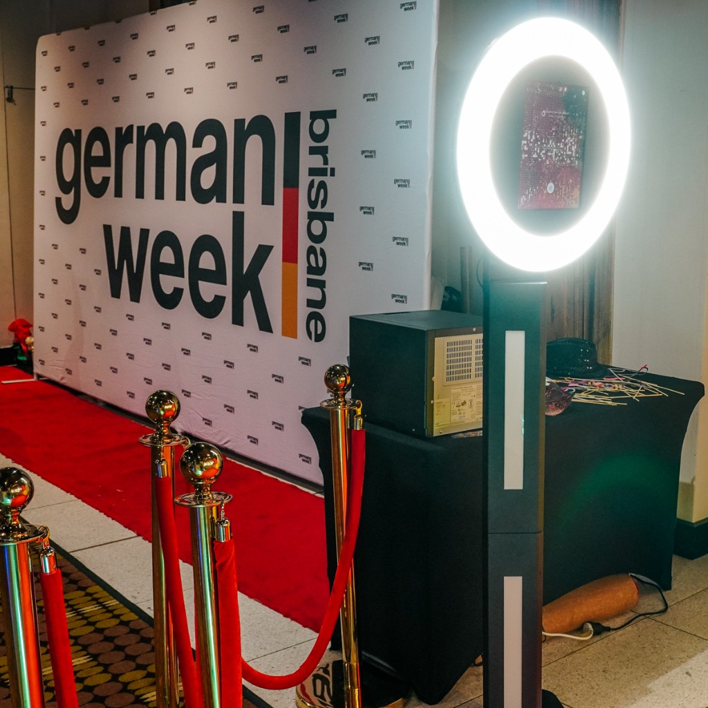 Open-air photobooth with ring light, red carpet, custom backdrop and props at a Brisbane event