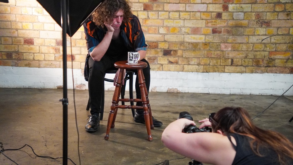 Professional videographer filming on location with studio lighting and brick backdrop